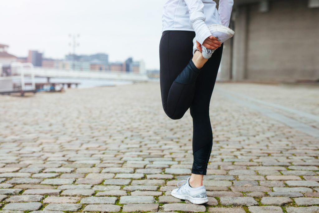 Fit young woman stretching her leg before a run