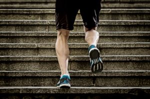 legs of young sport man with sharp scarf muscles running on staircase steps jogging in urban training