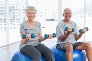 happy senior couple sitting on fitness balls